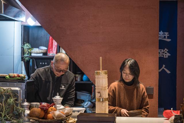 (260121) -- LIJIANG, Jan. 21, 2026 (Xinhua) -- He Dehua and his wife prepare snacks at the "Wayfarers" music club at the ancient city of Lijiang, southwest China's Yunnan Province, Jan. 16, 2026. He Dehua, 51, and his wife refurbished an old house of theirs in October 2025, and turned it into a music club called "Wayfarers," where they can share their personal stories with travelers and long-lost friends.
   The name "Wayfarers" came from a CD He had co-produced, drawing inspiration from his memory of watching elders of the family leaving hometown to work for livelihood. "We are all wayfarers in our own life, but we must not forget to search for the truth of life and the true self," said He.
   He has been a career musician for about three decades since he went to learn guitar playing in Beijing in 1997. Back to his hometown in Lijiang, he started to challenge himself by impressing the visitors to this olden city with music, songs and sounds of nature.
   He set out to collect voices and sounds in 2011, and has garnered more than 200 hours of recordings, which included some intangible cultural heritage items, voices in routine life, and melodies performed by folk artists. (Xinhua/Wang Guansen)