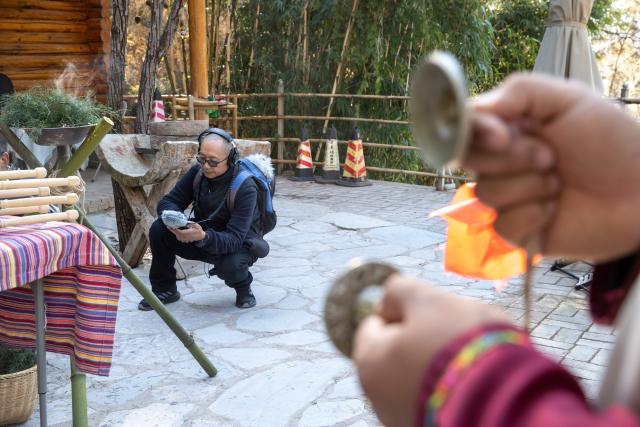 (260121) -- LIJIANG, Jan. 21, 2026 (Xinhua) -- He Dehua collects sounds at a park at the ancient city of Lijiang, southwest China's Yunnan Province, Jan. 16, 2026. He Dehua, 51, and his wife refurbished an old house of theirs in October 2025, and turned it into a music club called "Wayfarers," where they can share their personal stories with travelers and long-lost friends.
   The name "Wayfarers" came from a CD He had co-produced, drawing inspiration from his memory of watching elders of the family leaving hometown to work for livelihood. "We are all wayfarers in our own life, but we must not forget to search for the truth of life and the true self," said He.
   He has been a career musician for about three decades since he went to learn guitar playing in Beijing in 1997. Back to his hometown in Lijiang, he started to challenge himself by impressing the visitors to this olden city with music, songs and sounds of nature.
   He set out to collect voices and sounds in 2011, and has garnered more than 200 hours of recordings, which included some intangible cultural heritage items, voices in routine life, and melodies performed by folk artists. (Xinhua/Jiang Wenyao)