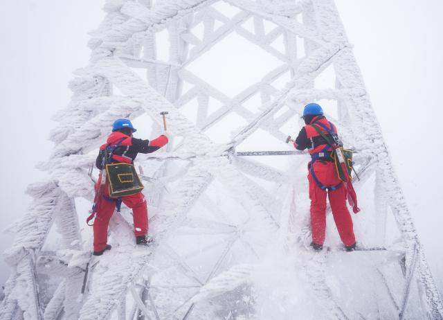 (260121) -- WUHAN, Jan. 21, 2026 (Xinhua) -- Workers deice on a power tower in Zouma Town of Hefeng County, central China's Hubei Province, Jan. 21, 2026. Facing widespread low-temperature with severe icing on power lines in some high-altitude areas in Hubei Province, power maintenance staff conducted patrols to ensure the stable operation of the power grid. (Photo by Qin Tao/Xinhua)