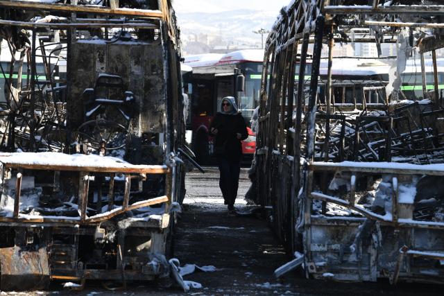 (260121) -- TEHRAN, Jan. 21, 2026 (Xinhua) -- A woman stands between destroyed buses during recent unrest in Tehran, Iran, Jan. 21, 2026. Iran's state television IRIB reported on Wednesday that 3,117 people were killed during recent unrest, citing the country's Forensic Medical Organization. (Xinhua/Shadati)