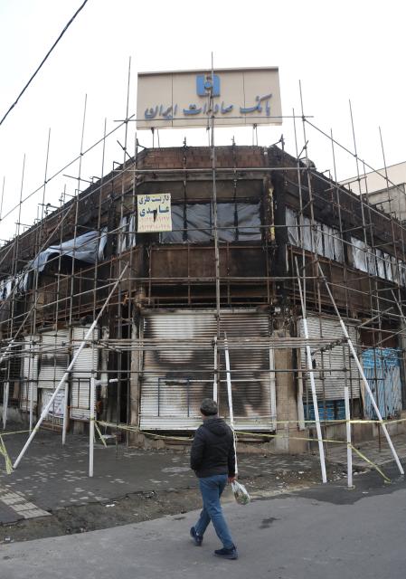 (260121) -- TEHRAN, Jan. 21, 2026 (Xinhua) -- A pedestrian passes in front of a bank branch building damaged during the recent unrest in Tehran, Iran, Jan. 21, 2026. Iran's state television IRIB reported on Wednesday that 3,117 people were killed during recent unrest, citing the country's Forensic Medical Organization. (Xinhua/Shadati)