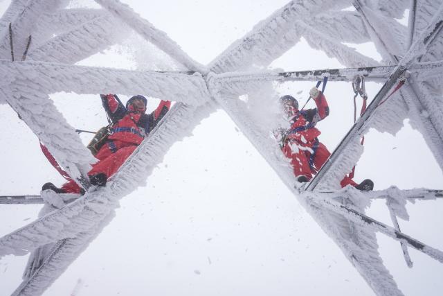 (260122) -- BEIJING, Jan. 22, 2026 (Xinhua) -- Workers deice on a power tower in Zouma Town of Hefeng County, central China's Hubei Province, Jan. 21, 2026. Facing widespread low-temperature with severe icing on power lines in some high-altitude areas in Hubei Province, power maintenance staff conducted patrols to ensure the stable operation of the power grid. (Photo by Qin Tao/Xinhua)
