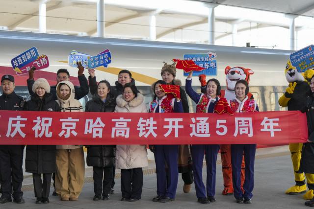 (260122) -- HARBIN, Jan. 22, 2026 (Xinhua) -- Train attendants pose for a group photo with passengers at the Harbin West Railway Station in Harbin, northeast China's Heilongjiang Province, on Jan. 22, 2026. The Beijing-Harbin high-speed railway marked the 5th anniversary of its full operation on Thursday. At 1,198 kilometers, the rail line links China's northeastern provinces of Liaoning, Jilin and Heilongjiang with the capital Beijing. (Xinhua/Wang Song)