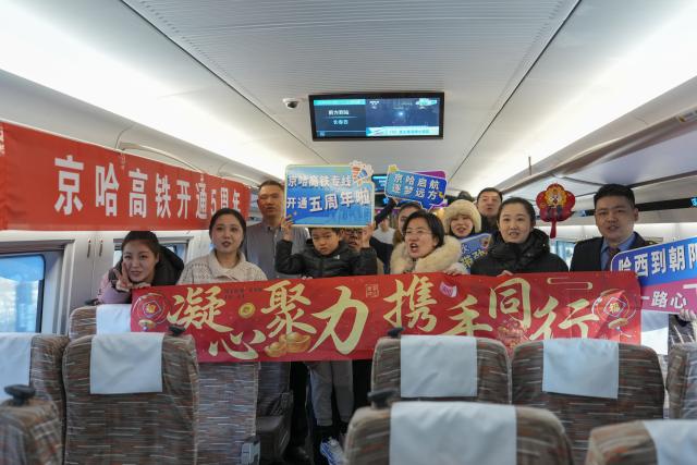 (260122) -- HARBIN, Jan. 22, 2026 (Xinhua) -- Train attendants pose for a group photo with passengers on bullet train G902 from Harbin, northeast China's Heilongjiang Province, to Beijing, capital of China, on Jan. 22, 2026. The Beijing-Harbin high-speed railway marked the 5th anniversary of its full operation on Thursday. At 1,198 kilometers, the rail line links China's northeastern provinces of Liaoning, Jilin and Heilongjiang with the capital Beijing. (Xinhua/Wang Song)