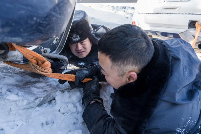 (260122) -- URUMQI, Jan. 22, 2026 (Xinhua) -- Police officers extricate a vehicle from snow in Urumqi, northwest China's Xinjiang Uygur Autonomous Region, on Jan. 19, 2026. A cold wave has swept across the region in recent days, with temperatures in parts of Altay Prefecture dropping to minus 47 degrees Celsius. Amid strong winds and snow, local authorities in charge of transport and energy sectors have coordinated their efforts to ensure uninterrupted heating service and daily supplies for the residents. (Photo by Ye Shuai/Xinhua)