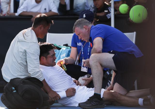 (260122) -- MELBOURNE, Jan. 22, 2026 (Xinhua) -- Wu Yibing (bottom) receives medical treatment after the men's singles 2nd round match between Wu Yibing of China and Eliot Spizzirri of the United States at the Australian Open tennis tournament in Melbourne, Australia, Jan. 22, 2026. (Xinhua/Ma Ping)