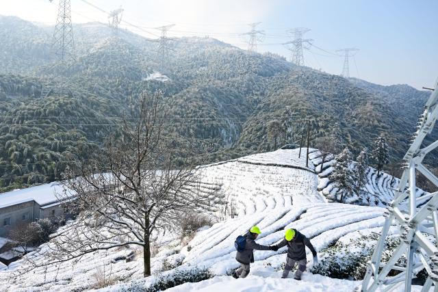 (260122) -- HEFEI, Jan. 22, 2026 (Xinhua) -- Gu Qingpu (L) and Li Wenke are on their way to an outpost in Jinzhai County, east China's Anhui Province, on Jan. 21, 2026. Ice coating were observed on part of the power transmission lines in Jinzhai County as a rigid cold wave swooped down here recently, posing a threat to grid operation.
   Gu Qingpu and Li Wenke, two Gen-Z power maintenance workers, braved the snow to show up at an outpost in Huangfan Village deep in the mountains. The outpost plays a key role in safeguarding the artery bringing power from the Three Gorges Hydro Power Station.
   Gu and Li work around the clock to report critical data such as temperature, humidity, wind speed, and ice coating thickness. They have to immediately start deicing operation in case of severe icing.
   "It's freezing cold and the job is tough. But we will fulfill our duty for every minute we are here to ensure the safety of the power lines," the duo said. (Xinhua/Zhou Mu)