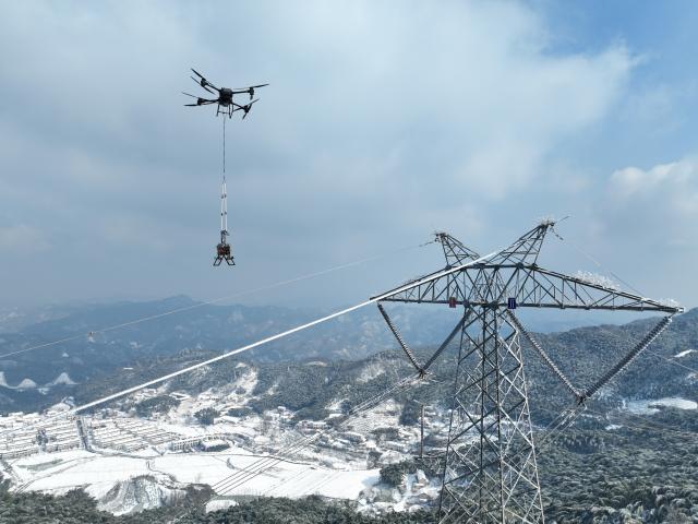 (260122) -- HEFEI, Jan. 22, 2026 (Xinhua) -- An aerial drone photo taken on Jan. 21, 2026 shows a drone, manipulated by Gu Qingpu, elevating a deicing device onto the power line, in Jinzhai County, east China's Anhui Province. Ice coating were observed on part of the power transmission lines in Jinzhai County as a rigid cold wave swooped down here recently, posing a threat to grid operation.
   Gu Qingpu and Li Wenke, two Gen-Z power maintenance workers, braved the snow to show up at an outpost in Huangfan Village deep in the mountains. The outpost plays a key role in safeguarding the artery bringing power from the Three Gorges Hydro Power Station.
   Gu and Li work around the clock to report critical data such as temperature, humidity, wind speed, and ice coating thickness. They have to immediately start deicing operation in case of severe icing.
   "It's freezing cold and the job is tough. But we will fulfill our duty for every minute we are here to ensure the safety of the power lines," the duo said. (Photo by Zhao Xianfu/Xinhua)