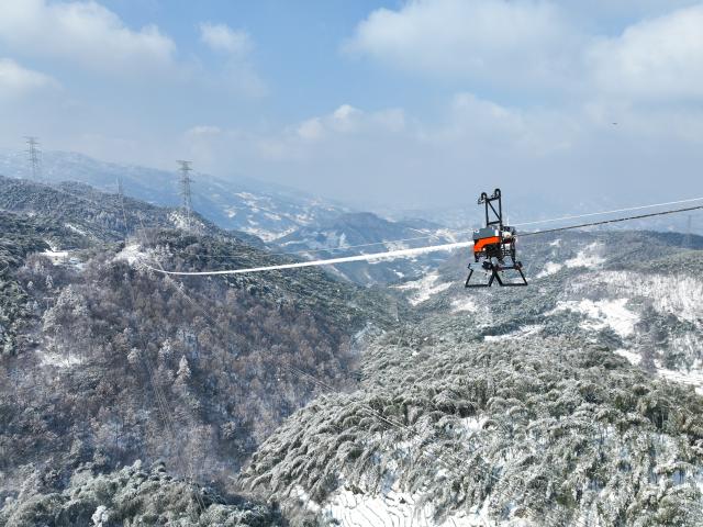 (260122) -- HEFEI, Jan. 22, 2026 (Xinhua) -- An aerial drone photo taken on Jan. 21, 2026 shows a deicing device operation on a power transmission line in Jinzhai County, east China's Anhui Province. Ice coating were observed on part of the power transmission lines in Jinzhai County as a rigid cold wave swooped down here recently, posing a threat to grid operation.
   Gu Qingpu and Li Wenke, two Gen-Z power maintenance workers, braved the snow to show up at an outpost in Huangfan Village deep in the mountains. The outpost plays a key role in safeguarding the artery bringing power from the Three Gorges Hydro Power Station.
   Gu and Li work around the clock to report critical data such as temperature, humidity, wind speed, and ice coating thickness. They have to immediately start deicing operation in case of severe icing.
   "It's freezing cold and the job is tough. But we will fulfill our duty for every minute we are here to ensure the safety of the power lines," the duo said. (Photo by Zhao Xianfu/Xinhua)