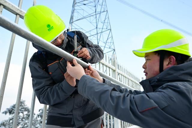 (260122) -- HEFEI, Jan. 22, 2026 (Xinhua) -- Gu Qingpu (L) and Li Wenke use a vernier caliper to measure the thickness of ice coating on a mock power line in Jinzhai County, east China's Anhui Province, on Jan. 21, 2026. Ice coating were observed on part of the power transmission lines in Jinzhai County as a rigid cold wave swooped down here recently, posing a threat to grid operation.
   Gu Qingpu and Li Wenke, two Gen-Z power maintenance workers, braved the snow to show up at an outpost in Huangfan Village deep in the mountains. The outpost plays a key role in safeguarding the artery bringing power from the Three Gorges Hydro Power Station.
   Gu and Li work around the clock to report critical data such as temperature, humidity, wind speed, and ice coating thickness. They have to immediately start deicing operation in case of severe icing.
   "It's freezing cold and the job is tough. But we will fulfill our duty for every minute we are here to ensure the safety of the power lines," the duo said. (Xinhua/Zhou Mu)