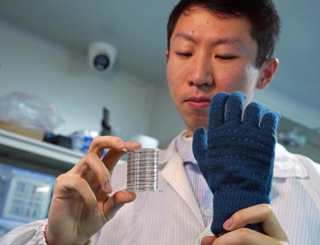 (260122) -- SHANGHAI, Jan. 22, 2026 (Xinhua) -- A researcher displays rolled-up "fiber chips" and a smart tactile glove made by weaving the chips into textiles at Fudan University in east China's Shanghai, Jan. 19, 2026. Scientists in China have created a flexible, thread-like "fiber chip" that can be woven into fabric, opening the door to garments that function as interactive screens, advanced brain implants capable of processing signals internally and hyperrealistic virtual reality touch.
   TO GO WITH "China Focus: Computing power woven into hair-thin fibers, paving way for smart clothes, brain implants" (Xinhua/Liu Ying)