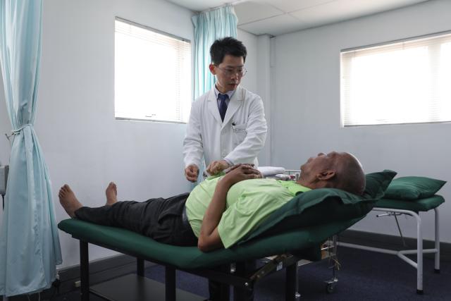 (260122) -- JOHANNESBURG, Jan. 22, 2026 (Xinhua) -- Hu Zijing (back), an associate professor at the University of Johannesburg and head of the African Center for Traditional Chinese Medicine and Acupuncture, gives acupuncture treatment to South African patient Jabulane Ngwenwa at the center in Johannesburg, South Africa, Jan. 21, 2026. TO GO WITH "Feature: Blending tradition, technology: AI-powered TCM brings new hope to South African patients" (Xinhua/Chen Wei)