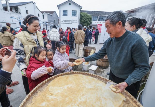 (260123) -- ZHUJI, Jan. 23, 2026 (Xinhua) -- Children taste freshly made rice cakes at a farmers' fair held to welcome the Chinese Lunar New Year in Dongbaihu Town of Zhuji City, east China's Zhejiang Province, Jan. 23, 2026. (Xinhua/Xu Yu)