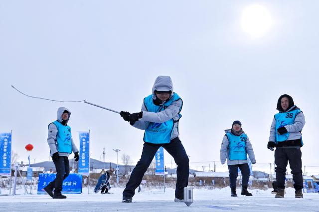 (260123) -- TONGJIANG, Jan. 23, 2026 (Xinhua) -- People of the Hezhe ethnic group participate in a folk sport during a winter fishing festival in Jiejinkou Hezhe Ethnic Township, Tongjiang City, northeast China's Heilongjiang Province, on Jan. 23, 2026. The event, held on a frozen lake, is part of the province's winter fishing events. It integrates traditional Hezhe fishing and hunting culture with folk sports, offering visitors an immersive experience of the icy landscape and unique Hezhe customs. (Photo by Liu Wanping/Xinhua)