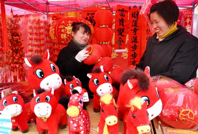 (260123) -- BEIJING, Jan. 23, 2026 (Xinhua) -- People select items for New Year celebration at a market in Wuyi County, Jinhua City of east China's Zhejiang Province, Jan. 23, 2026. Chinese people are busy preparing fresh flowers, Chinese knots, spring couplets, and other traditional necessities to celebrate the upcoming Spring Festival, or the Chinese New Year. (Photo by Zhang Jiancheng/Xinhua)