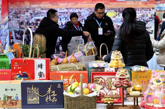 (260123) -- BEIJING, Jan. 23, 2026 (Xinhua) -- Customers select items for New Year celebration at a fair inside an exhibition center in Shijiazhuang, north China's Hebei Province, Jan. 23, 2026. Chinese people are busy preparing fresh flowers, Chinese knots, spring couplets, and other traditional necessities to celebrate the upcoming Spring Festival, or the Chinese New Year. (Photo by Chen Qibao/Xinhua)