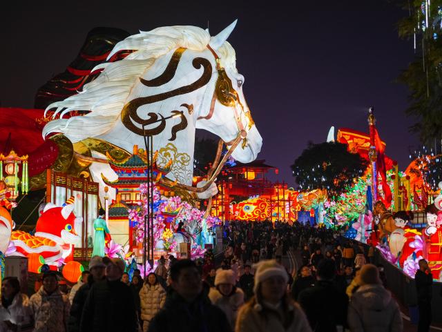 (260123) -- ZIGONG, Jan. 23, 2026 (Xinhua) -- Tourists visit the 32nd Zigong International Dinosaur Lantern Show in Zigong, southwest China's Sichuan Province, Jan. 23, 2026. All lanterns displayed at the show were lit up on Friday evening. This year's show features 11  groups of large light sets and more than 200 groups of small and medium-sized light sets. (Xinhua/Wang Xi)