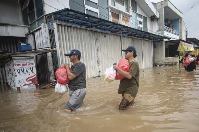 (260123) -- JAKARTA, Jan. 23, 2026 (Xinhua) -- People wade through floodwaters in South Tangerang, Banten Province, Indonesia, Jan. 23, 2026. (Photo by Agung Kuncahya B./Xinhua)