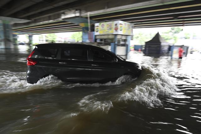 (260123) -- JAKARTA, Jan. 23, 2026 (Xinhua) -- A car drives through floodwaters in Jakarta, Indonesia, Jan. 23, 2026. (Xinhua/Zulkarnain)