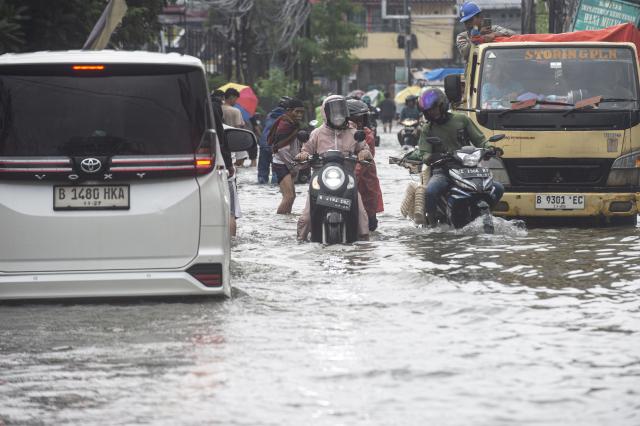(260123) -- JAKARTA, Jan. 23, 2026 (Xinhua) -- People ride motorbikes through floodwaters in Tangerang, Banten Province, Indonesia, Jan. 23, 2026. (Photo by Agung Kuncahya B./Xinhua)