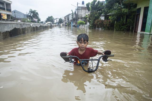(260123) -- JAKARTA, Jan. 23, 2026 (Xinhua) -- A boy pushes his bike through floodwaters in South Tangerang, Banten Province, Indonesia, Jan. 23, 2026. (Photo by Agung Kuncahya B./Xinhua)