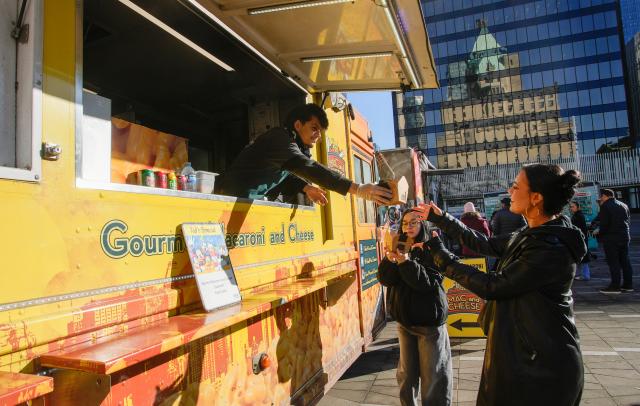 (260124) -- VANCOUVER, Jan. 24, 2026 (Xinhua) -- A vendor serves food to a customer from a food truck during the "Street Food City" event in Vancouver, British Columbia, Canada, Jan. 23, 2026. (Photo by Liang Sen/Xinhua)