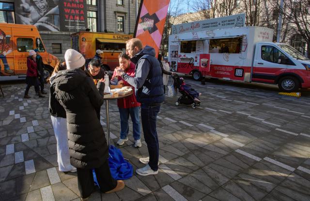 (260124) -- VANCOUVER, Jan. 24, 2026 (Xinhua) -- People enjoy their food ordered from food trucks during the "Street Food City" event in Vancouver, British Columbia, Canada, Jan. 23, 2026. (Photo by Liang Sen/Xinhua)