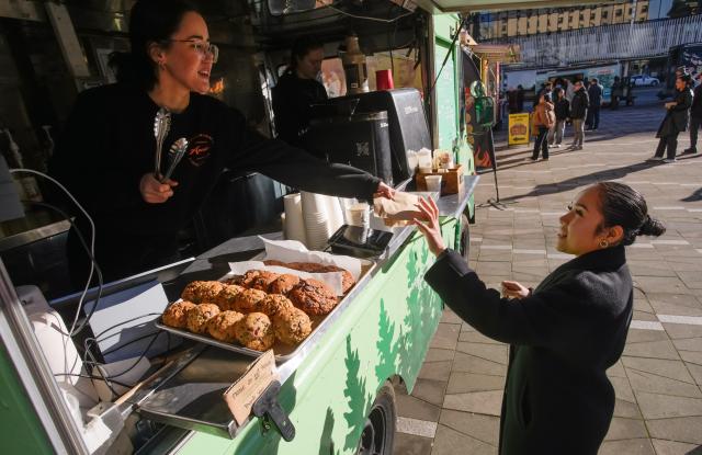 (260124) -- VANCOUVER, Jan. 24, 2026 (Xinhua) -- A vendor serves food to a customer from a food truck during the "Street Food City" event in Vancouver, British Columbia, Canada, Jan. 23, 2026. (Photo by Liang Sen/Xinhua)