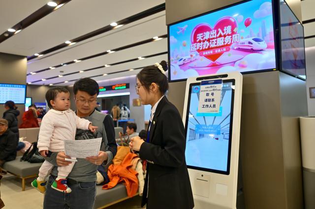 (260124) -- TIANJIN, Jan. 24, 2026 (Xinhua) -- A staff member provides information to citizens at the exit-entry services hall of Tianjin Municipal Public Security Bureau in north China's Tianjin Municipality, Jan. 24, 2026. The exit-entry administration division of Tianjin Municipal Public Security Bureau on Saturday launched a campaign to facilitate the processing of travel documents during the peak travel season around the Spring Festival holiday. Citizens can expect shorter waiting times as more service counters are opened and service hours are extended. (Xinhua/Sun Fanyue)