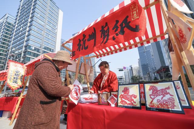(260124) -- HANGZHOU, Jan. 24, 2026 (Xinhua) -- A citizen views paper-cutting works during a fair featuring intangible cultural heritage and Chinese New Year goods in Hangzhou, east China's Zhejiang Province, on Jan. 24, 2026. Kicking off in Hangzhou on Saturday, the event blends traditional festivities with modern trends, offering visitors an immersive experience of cultural crafts, holiday shopping, and folk performances. (Xinhua/Xu Yu)