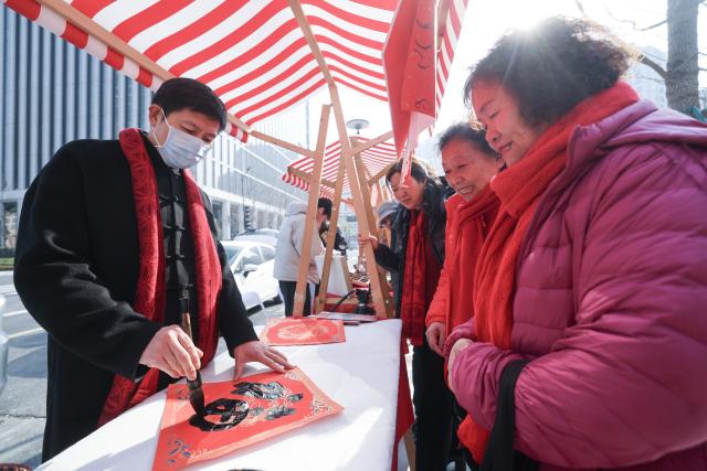(260124) -- HANGZHOU, Jan. 24, 2026 (Xinhua) -- A calligrapher writes the Chinese character "Fu" (meaning "Fortune") as presents for visitors during a fair featuring intangible cultural heritage and Chinese New Year goods in Hangzhou, east China's Zhejiang Province, on Jan. 24, 2026. Kicking off in Hangzhou on Saturday, the event blends traditional festivities with modern trends, offering visitors an immersive experience of cultural crafts, holiday shopping, and folk performances. (Xinhua/Xu Yu)