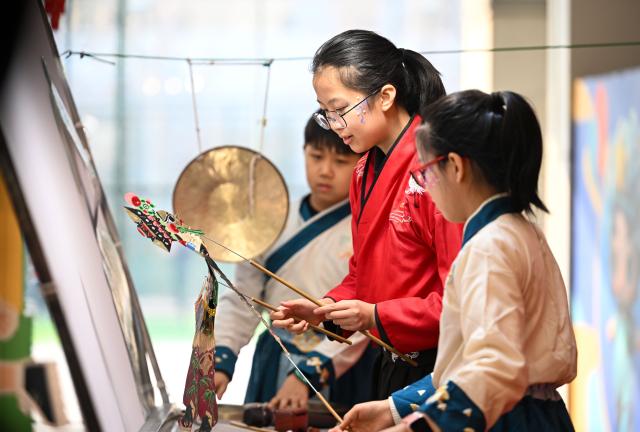 (260124) -- TIANJIN, Jan. 24, 2026 (Xinhua) -- Children try to play shadow puppets during a temple fair for children in north China's Tianjin, on Jan. 24, 2026. A special temple fair tailored for children kicked off in north China's Tianjin on Saturday. Crowds of parents and kids gathered at the fair to experience the festive atmosphere ahead of the Spring Festival. The event features a variety of activities including traditional handicraft making, Tianjin-style food tasting, and interactive games. (Xinhua/Zhao Zishuo)