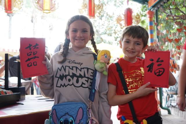 (260124) -- ANAHEIM, Jan. 24, 2026 (Xinhua) -- Children display the Chinese calligraphy works they received as gifts during the Lunar New Year celebrations at Disney California Adventure Park in Anaheim, California, the United States, Jan. 23, 2026. Disneyland Resort kicked off its annual Lunar New Year celebrations on Friday, transforming the park into a vibrant showcase of Asian cultures, cuisine and traditions that continues to attract growing interest from U.S. visitors.
   TO GO WITH "Feature: Disneyland's Lunar New Year celebrations offer immersive window into Asian cultures" (Photo by Zeng Hui/Xinhua)