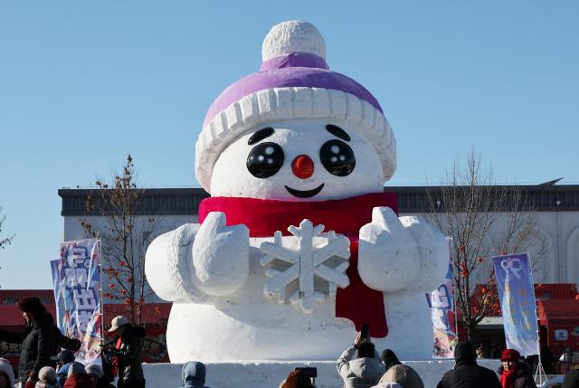 (260124) -- SHENYANG, Jan. 24, 2026 (Xinhua) -- Tourists take photos of a giant snowman during a winter fishing event at Wolong Lake in Kangping County of Shenyang, northeast China's Liaoning Province, Jan. 24, 2026. A winter fishing event began here on Saturday, featuring performances, fish cuisine, and ice and snow recreational facilities. (Xinhua/Li Gang)
