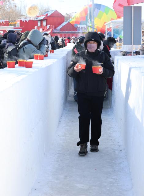 (260124) -- SHENYANG, Jan. 24, 2026 (Xinhua) -- Tourists enjoy fish soup and ginger tea during a winter fishing event at Wolong Lake in Kangping County of Shenyang, northeast China's Liaoning Province, Jan. 24, 2026. A winter fishing event began here on Saturday, featuring performances, fish cuisine, and ice and snow recreational facilities. (Xinhua/Han He)