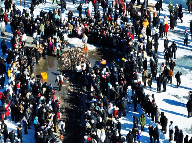 (260124) -- SHENYANG, Jan. 24, 2026 (Xinhua) -- An aerial drone photo taken on Jan. 24, 2026 shows people watching a fish-catching activity at Wolong Lake in Kangping County of Shenyang, northeast China's Liaoning Province. A winter fishing event began here on Saturday, featuring performances, fish cuisine, and ice and snow recreational facilities. (Xinhua/Li Gang)