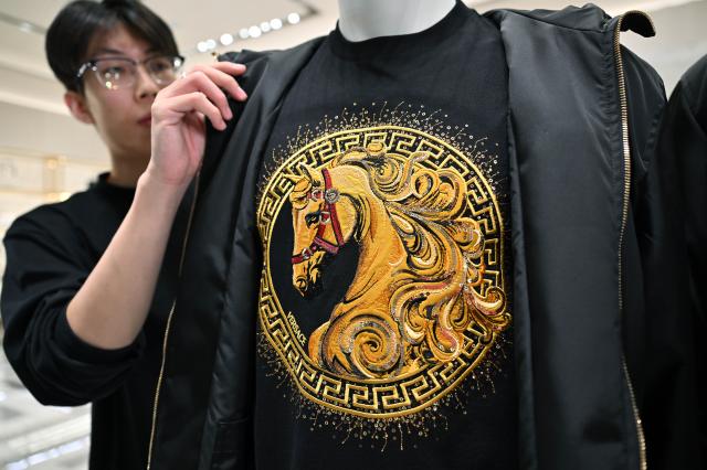 (260124) -- HAIKOU, Jan. 24, 2026 (Xinhua) -- A staff member displays Year of the Horse themed clothes at Haikou International Duty Free Shopping Complex in Haikou, south China's Hainan Province, Jan. 24, 2026. With the Year of the Horse approaching, many international brands have incorporated Chinese zodiac culture and traditional Chinese design elements into their products, launching Year of the Horse editions to compete in the Chinese Lunar New Year market. (Xinhua/Guo Cheng)
