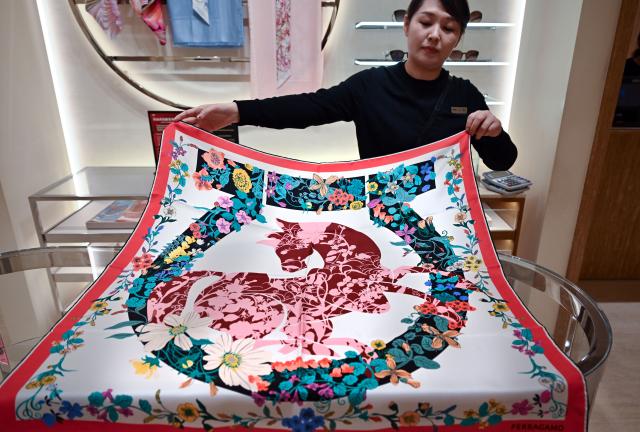 (260124) -- HAIKOU, Jan. 24, 2026 (Xinhua) -- A staff member displays a Year of the Horse themed scarf at Haikou International Duty Free Shopping Complex in Haikou, south China's Hainan Province, Jan. 24, 2026. With the Year of the Horse approaching, many international brands have incorporated Chinese zodiac culture and traditional Chinese design elements into their products, launching Year of the Horse editions to compete in the Chinese Lunar New Year market. (Xinhua/Guo Cheng)