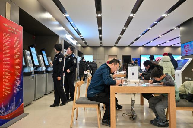 (260125) -- BEIJING, Jan. 25, 2026 (Xinhua) -- Citizens fill out paperwork at the exit-entry services hall of Tianjin Municipal Public Security Bureau in north China's Tianjin Municipality, Jan. 24, 2026. The exit-entry administration division of Tianjin Municipal Public Security Bureau on Saturday launched a campaign to facilitate the processing of travel documents during the peak travel season around the Spring Festival holiday. Citizens can expect shorter waiting times as more service counters are opened and service hours are extended. (Xinhua/Sun Fanyue)