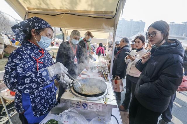 (260125) -- HANGZHOU, Jan. 25, 2026 (Xinhua) -- A vendor prepares food at a theme event promoting the culture and tourism of Jiande City, in Hangzhou, east China's Zhejiang Province, Jan. 24, 2026. On Saturday, a theme event promoting the culture and tourism of Jiande City in Zhejiang Province was launched in Hangzhou. Female entrepreneurs from 16 towns and sub-districts in Jiande brought a variety of handmade delicacies and local agricultural products such as tofu buns, eggs, strawberries, lotus seeds, tea, and dried fish to the public.
   In recent years, Jiande City has helped local women achieve employment at home through e-commerce and live-streaming, greatly increasing women's income. (Xinhua/Xu Yu)