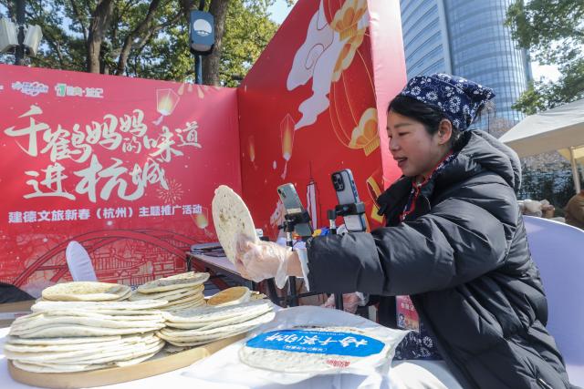 (260125) -- HANGZHOU, Jan. 25, 2026 (Xinhua) -- A vendor promotes food products via live-streaming at a theme event promoting the culture and tourism of Jiande City, in Hangzhou, east China's Zhejiang Province, Jan. 24, 2026. On Saturday, a theme event promoting the culture and tourism of Jiande City in Zhejiang Province was launched in Hangzhou. Female entrepreneurs from 16 towns and sub-districts in Jiande brought a variety of handmade delicacies and local agricultural products such as tofu buns, eggs, strawberries, lotus seeds, tea, and dried fish to the public.
   In recent years, Jiande City has helped local women achieve employment at home through e-commerce and live-streaming, greatly increasing women's income. (Xinhua/Xu Yu)