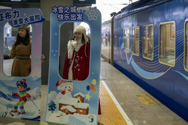 (260125) -- HARBIN, Jan. 25, 2026 (Xinhua) -- Staff members show costumes for travel photography beside the Train Y783 at the platform of Harbin East Railway Station in Harbin, northeast China's Heilongjiang Province, Jan. 25, 2026. Train Y783, a themed tourism train bound for Yabuli featuring travel photography services, was inaugurated Sunday in Harbin. It marks the company's first offering of its kind this year. Operated by China Railway Harbin Group Co., Ltd., the train allows passengers to dress in diverse costumes and avail themselves of photography services. (Xinhua/Zhang Tao)