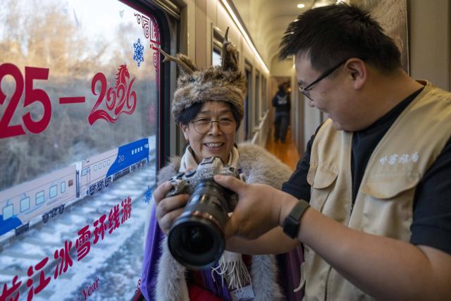 (260125) -- HARBIN, Jan. 25, 2026 (Xinhua) -- A passenger views her photos on the camera of a photographer on the Train Y783 in northeast China's Heilongjiang Province, Jan. 25, 2026. Train Y783, a themed tourism train bound for Yabuli featuring travel photography services, was inaugurated Sunday in Harbin. It marks the company's first offering of its kind this year. Operated by China Railway Harbin Group Co., Ltd., the train allows passengers to dress in diverse costumes and avail themselves of photography services. (Xinhua/Zhang Tao)