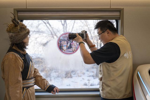 (260125) -- HARBIN, Jan. 25, 2026 (Xinhua) -- A photographer takes photos of a passenger on the Train Y783 in northeast China's Heilongjiang Province, Jan. 25, 2026. Train Y783, a themed tourism train bound for Yabuli featuring travel photography services, was inaugurated Sunday in Harbin. It marks the company's first offering of its kind this year. Operated by China Railway Harbin Group Co., Ltd., the train allows passengers to dress in diverse costumes and avail themselves of photography services. (Xinhua/Zhang Tao)