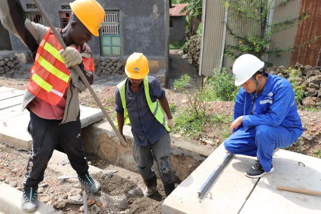 (260125) -- KIGALI, Jan. 25, 2026 (Xinhua) -- Chinese engineer Zhou Chunyi (R) works with local colleagues along a road constructed by China Road and Bridge Corporation in Burera District, Rwanda's Northern Province, Jan. 21, 2026. TO GO WITH "Feature: Chinese-built road transforms lives, boosts economy in northern Rwanda" (Xinhua/Ju Yinhe)