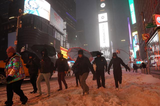 (260126) -- NEW YORK, Jan. 26, 2026 (Xinhua) -- People walk amid snow at Times Square in New York, the United States, on Jan. 25, 2026. A historic winter storm is sweeping across the Midwest and eastern parts of the United States on Sunday, causing unprecedented travel chaos. (Xinhua/Zhang Fengguo)