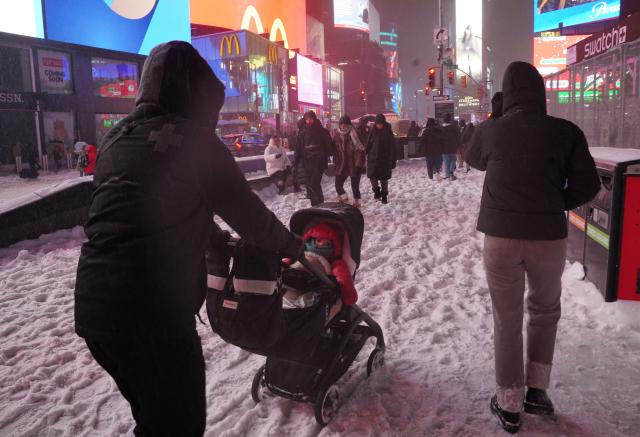 (260126) -- NEW YORK, Jan. 26, 2026 (Xinhua) -- People walk amid snow at Times Square in New York, the United States, on Jan. 25, 2026. A historic winter storm is sweeping across the Midwest and eastern parts of the United States on Sunday, causing unprecedented travel chaos. (Xinhua/Zhang Fengguo)
