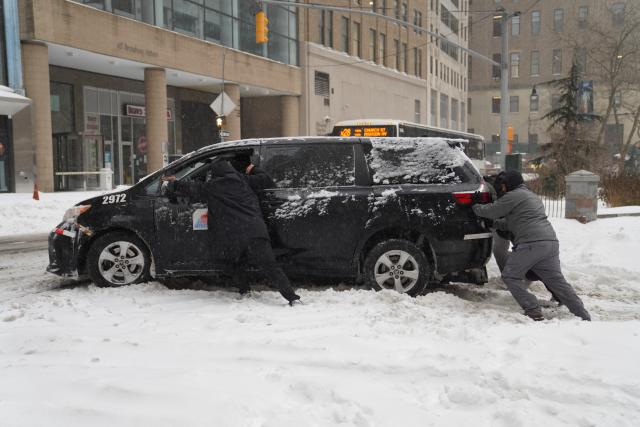 (260126) -- NEW YORK, Jan. 26, 2026 (Xinhua) -- People push a car stuck in snow in New York, the United States, on Jan. 25, 2026. A historic winter storm is sweeping across the Midwest and eastern parts of the United States on Sunday, causing unprecedented travel chaos. (Xinhua/Zhang Fengguo)