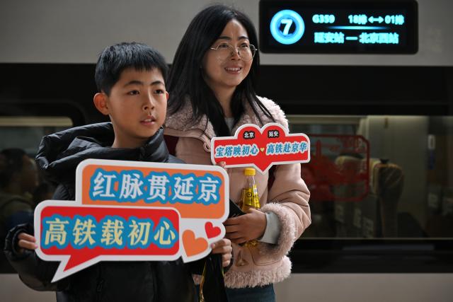 (260126) -- XI'AN, Jan. 26, 2026 (Xinhua) -- Passengers pose for photos with the first high-speed train from Yan'an to the capital city of Beijing at Yan'an Station in Yan'an, northwest China's Shaanxi Province, Jan. 26, 2026. The high-speed train G359 departed from Yan'an on Monday morning, marking the first direct connection of high-speed rail from the sacred revolutionary site to the nation's capital city of Beijing.
   The fastest high-speed train ride from Yan'an to Beijing will take five hours and 42 minutes, a big improvement compared to the original train. (Xinhua/Li Yibo)
