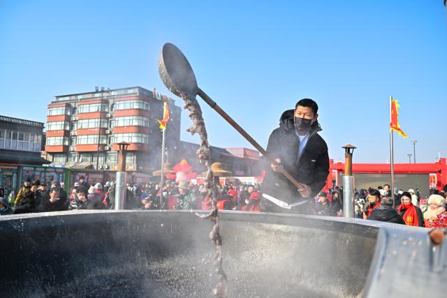 (260126) -- TIANJIN, Jan. 26, 2026 (Xinhua) -- A staff member makes Laba porridge at an open air market during the Laba Festival in Tianjin, north China, Jan. 26, 2026. This year's Laba Festival falls on Monday, coinciding with the opening of the Lutai Market in Tianjin. The market features traditional activities such as free distribution of Laba porridge, calligraphy of the character "Fu" for blessings, and a village chef competition, attracting numerous residents from surrounding areas. (Xinhua/Sun Fanyue)